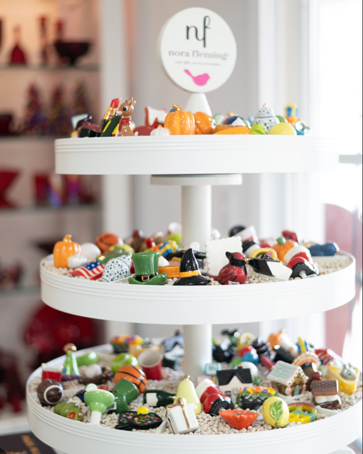 Three-tiered white cake stand with decorative items on a blurred background